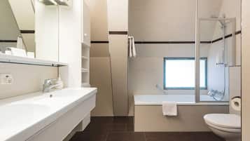 A modern bathroom with a large mirror, a white sink, a bathtub, and a toilet.