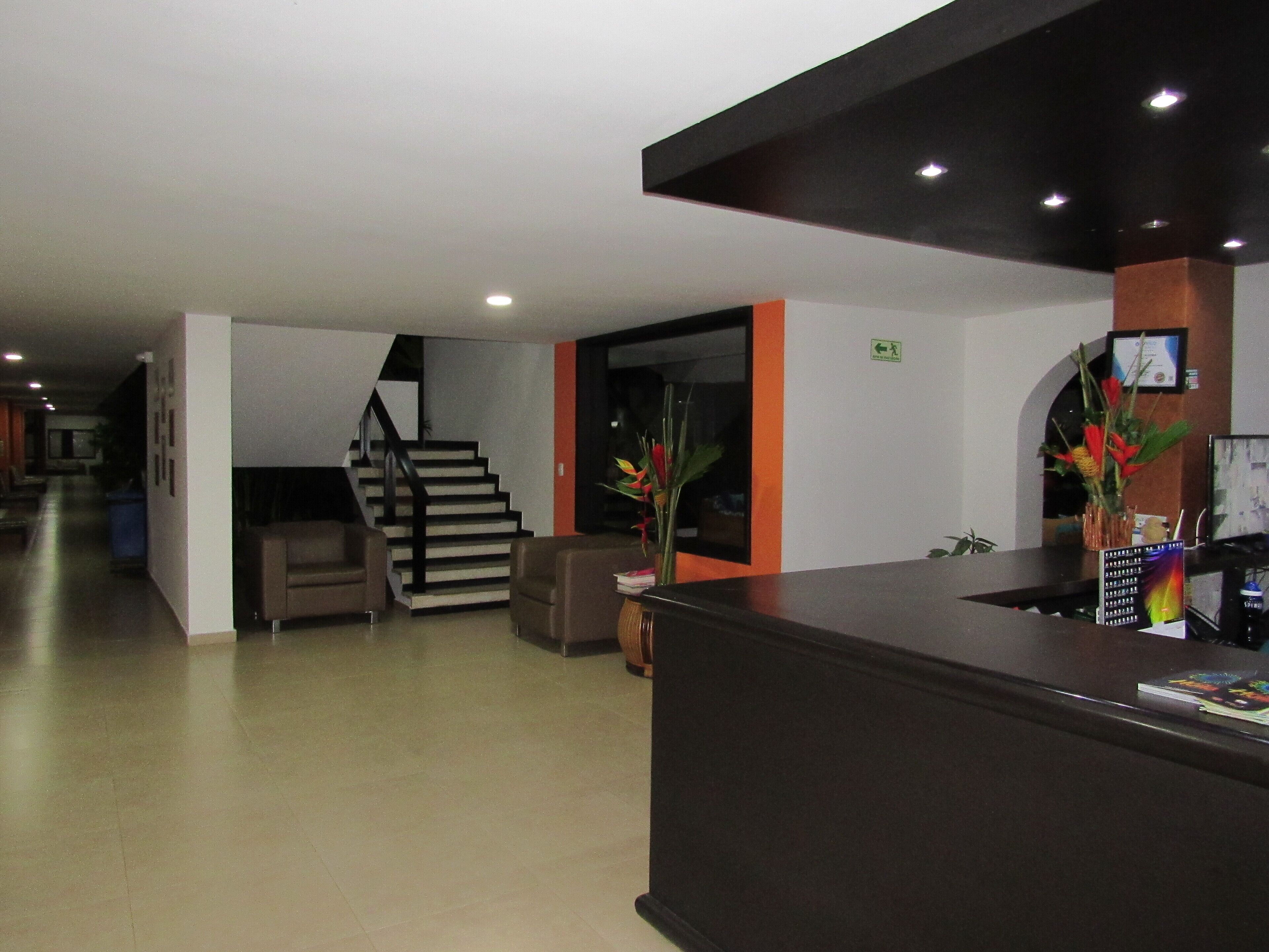 Un área de recepción con mostrador, escalera y zona de estar.