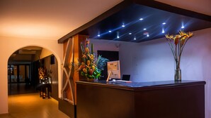 Un mostrador de recepción de diseño moderno, una computadora y un jarrón con flores.