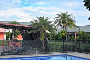 A pool area with a slide, outdoor seating, and palm trees.