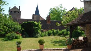 A courtyard with a stone wall, a tower, and a building with a blue roof.