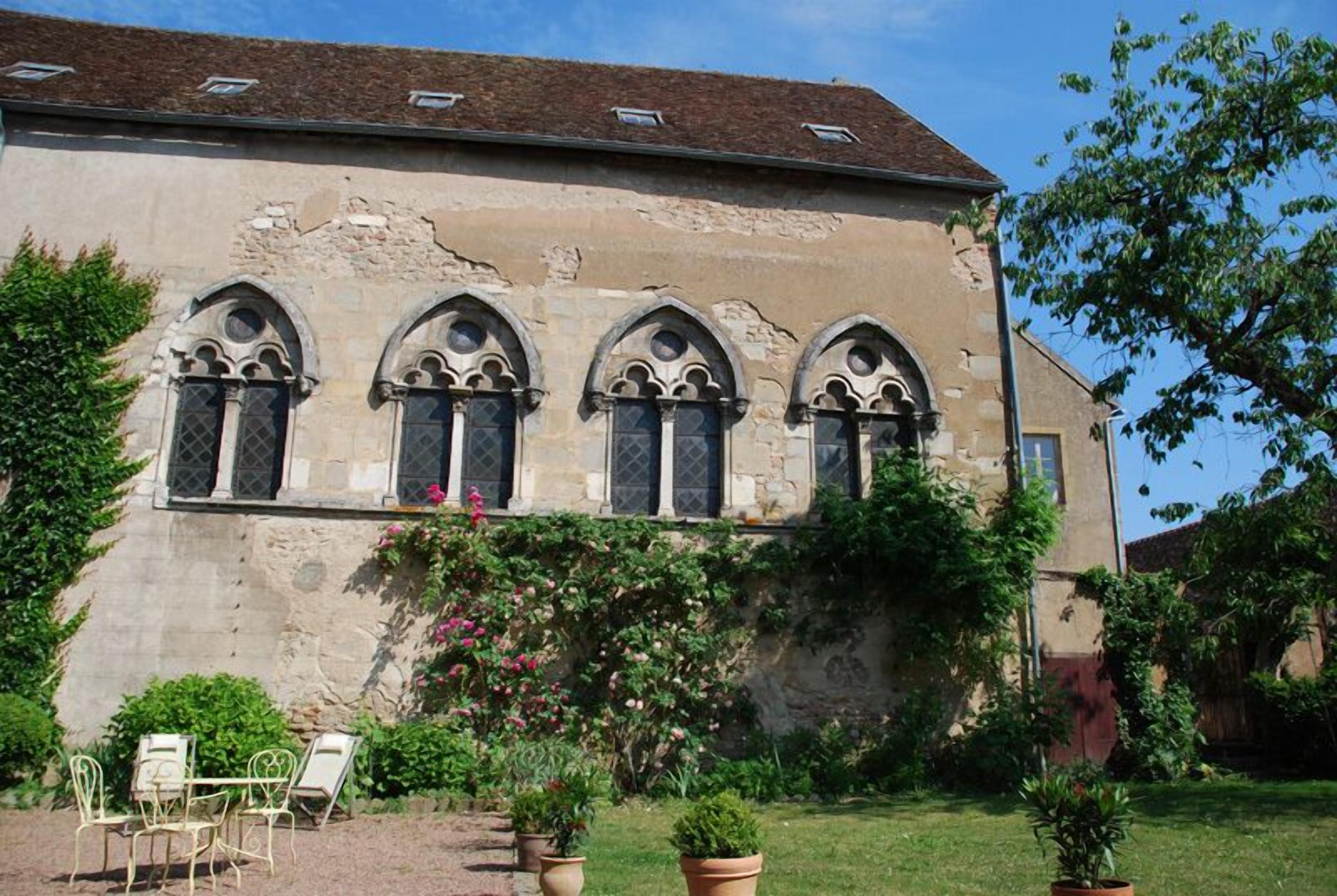 Um edifício histórico com janelas em arco e um jardim com área de estar ao ar livre.