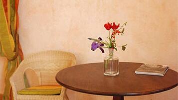Uma mesa de madeira redonda com um vaso de flores, uma cadeira com almofada e um quadro pendurado na parede.