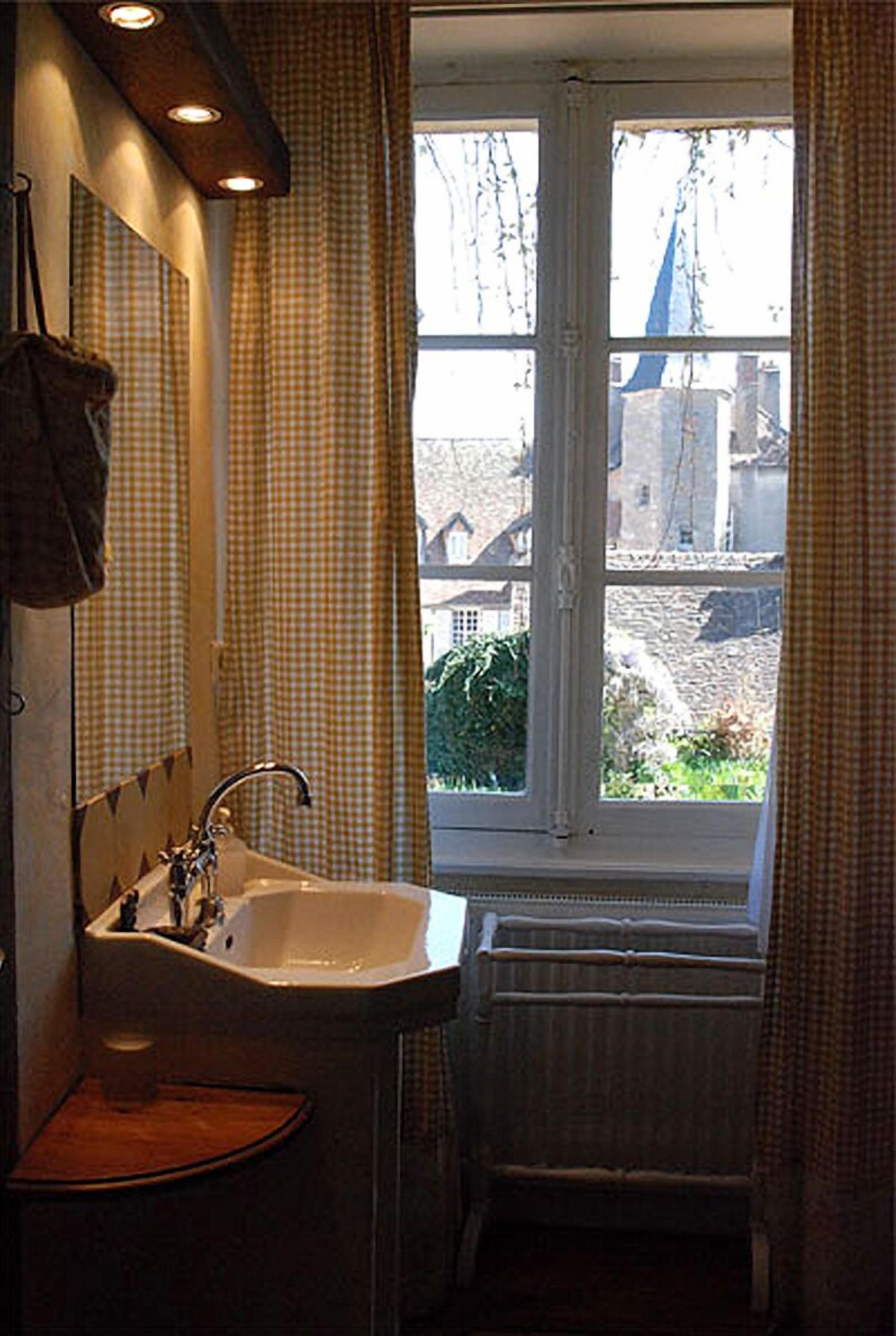 Une salle de bain avec une fenêtre, un lavabo et un miroir.