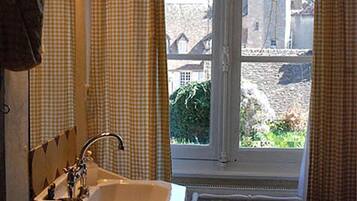 Une salle de bain avec une fenêtre, un lavabo et un miroir.