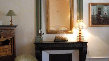 Una stanza con camino, uno specchio, una lampada e un quadro appeso al muro.