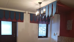 Een slaapkamer met een bed, een bureau, een stoel, een raam en een kroonluchter.