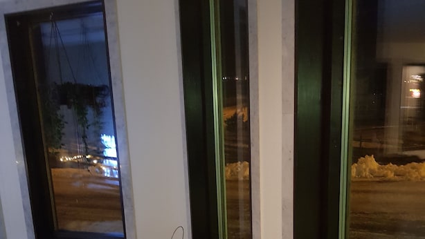 Een modern interieur met een houten bankje, een bont plaid en een lantaarn op een tafel.