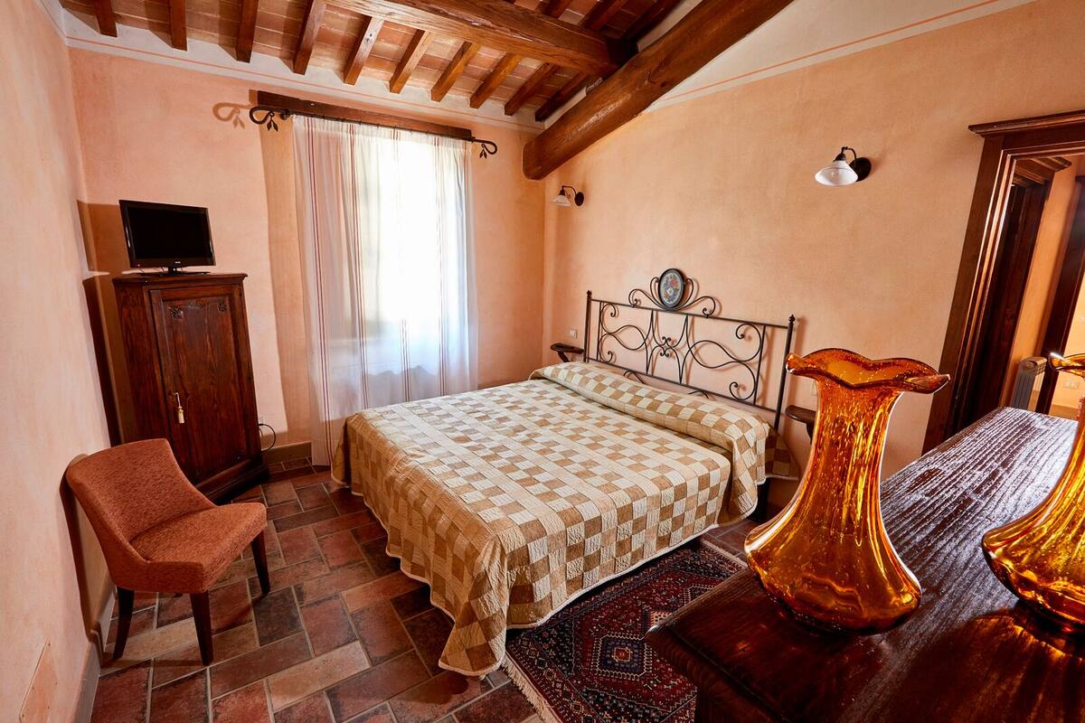 A bedroom with a bed, a chair, a cabinet, and a vase.