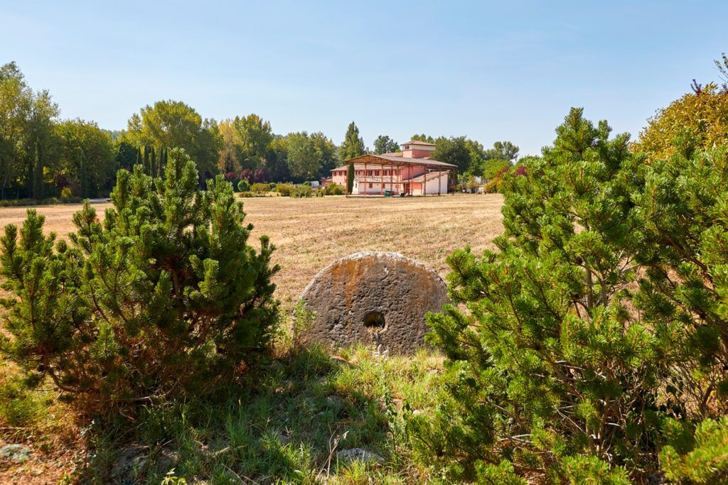 Un paysage rural avec une maison et un puits en pierre.