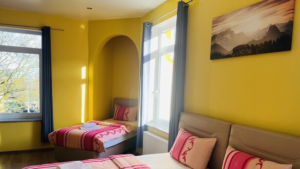 Ett hotellrum med två sängar, ett stort fönster och en tavla på väggen.