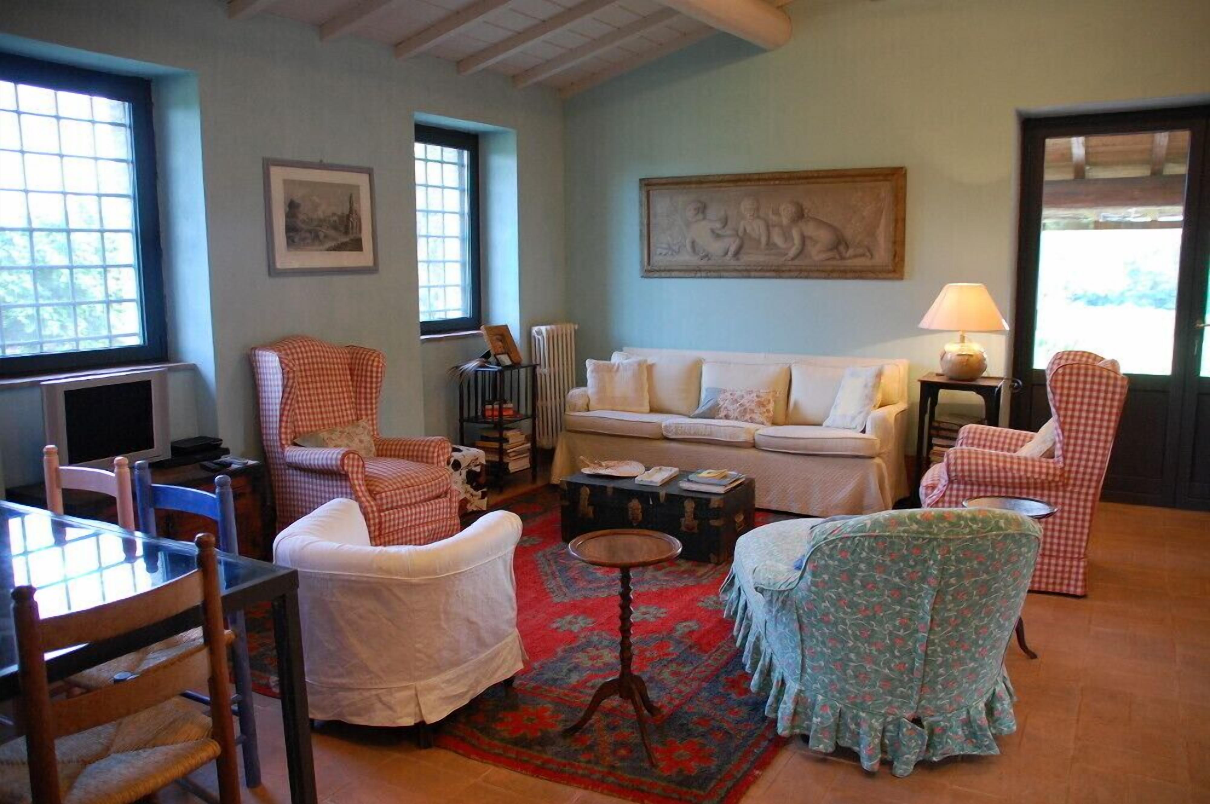 A cozy living room with a sofa, armchairs, a table, and a patterned rug.