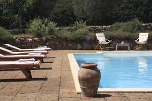 A poolside area with lounge chairs and a large terracotta pot. - Verdidea - Bagnoletto (Orte)
