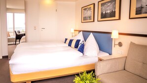 Una habitación de hotel con una cama grande, un sofá y dos cuadros en la pared.