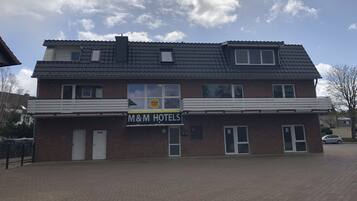 A two-story M&M Hotels building with a brick facade, large windows, and a flat roof.