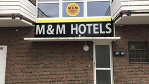 A building with a sign reading "M&M HOTELS PENSION". - M&M Hotel - Neu Wulmstorf (Neu Wulmstorf)