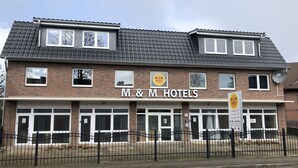 A two-story M&M Hotels building with a brick facade, multiple windows, and a gated entrance. - M&M Hotel - Neu Wulmstorf (Neu Wulmstorf)
