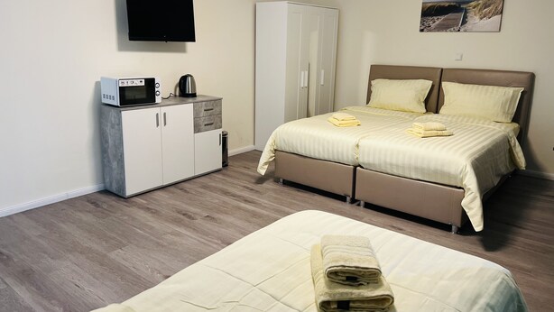 A bedroom with a bed, a wardrobe, a television, and a painting on the wall. - M&M Hotel - Neu Wulmstorf (Neu Wulmstorf)