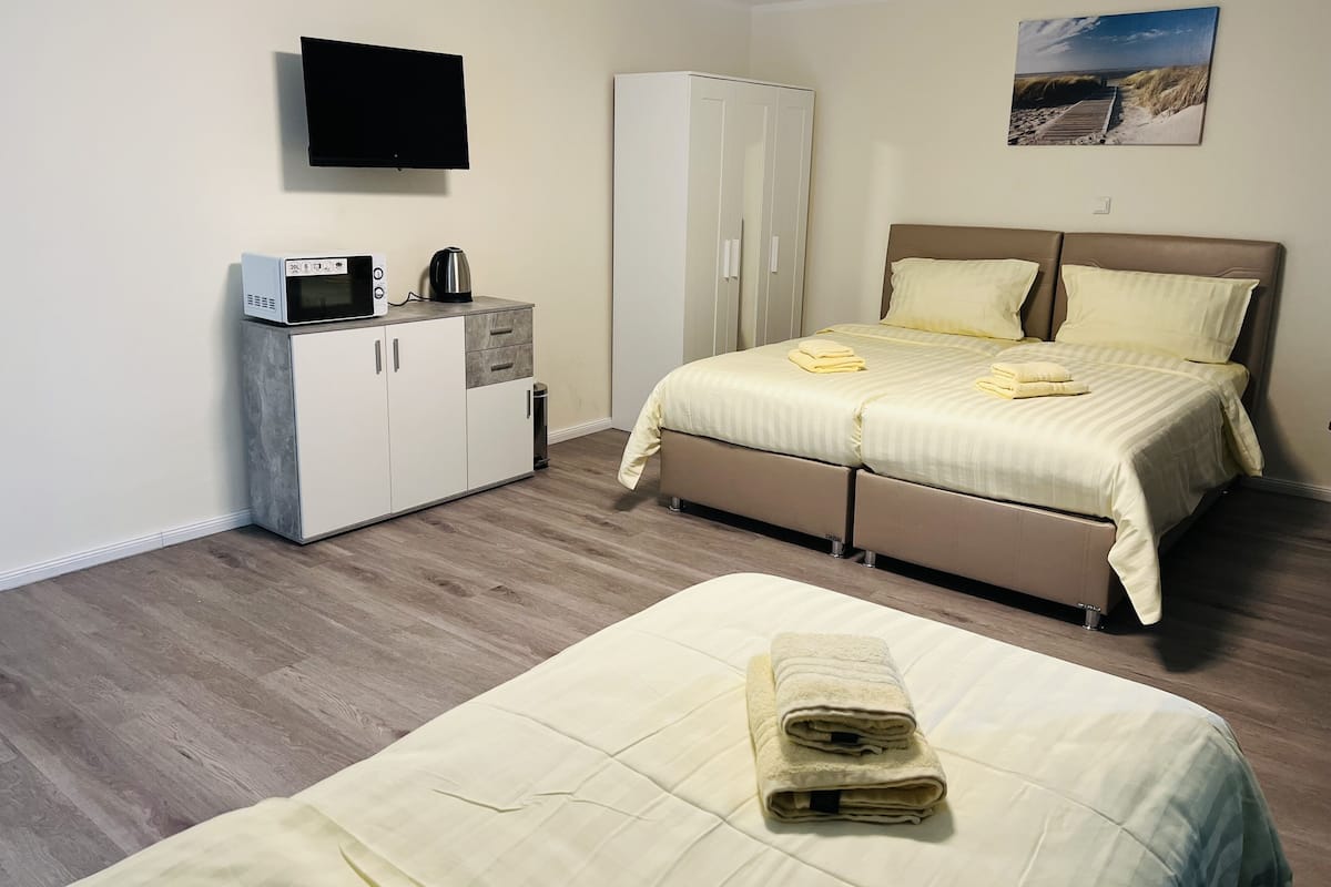 Une chambre à coucher avec un lit, une armoire, un téléviseur et un tableau accroché au mur.