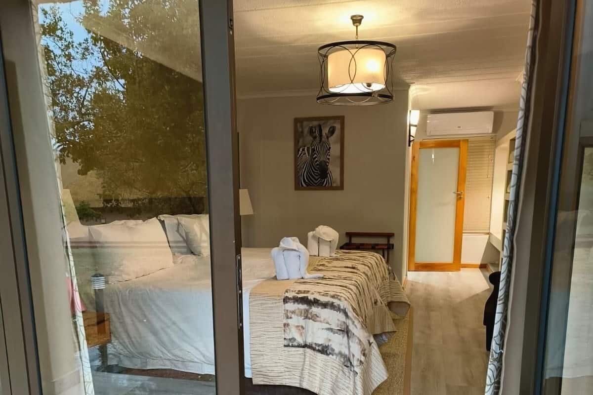 A bedroom with a bed, a zebra artwork, a ceiling light, and a sliding glass door leading to an outdoor area.