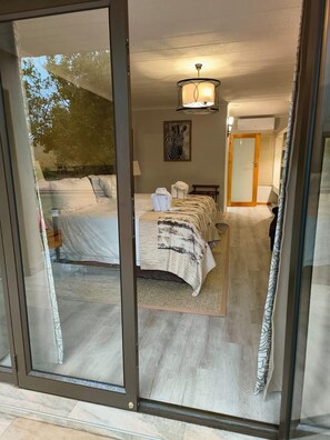 A bedroom with a bed, a zebra artwork, a ceiling light, and a sliding glass door leading to an outdoor area. - BushTime at Mabula (Bela-Bela, Limpopo)