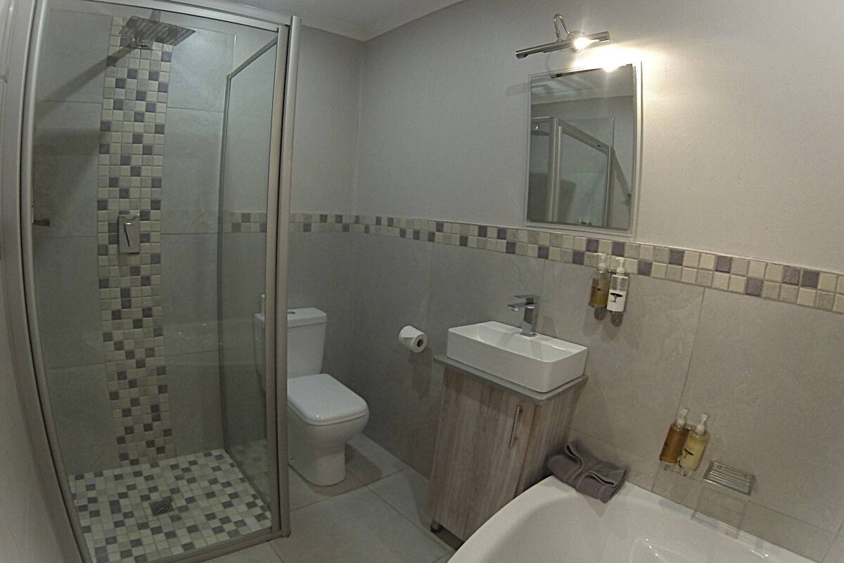 A bathroom with a glass-enclosed shower, a toilet, a sink, and a bathtub.