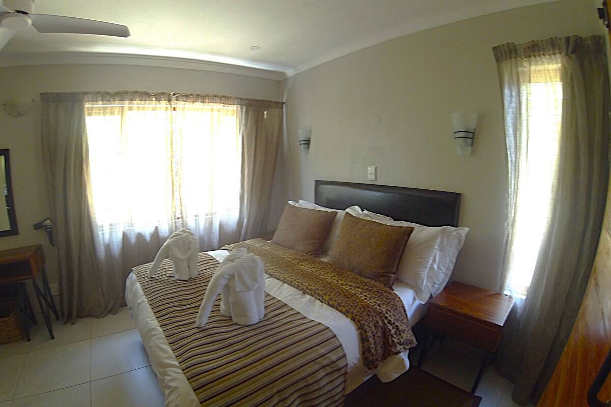 A hotel room with a bed, a nightstand, a lamp, and a ceiling fan.