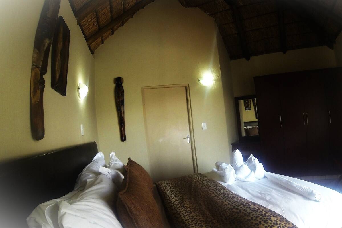 A hotel room with a bed, a wardrobe, a door, and a wall-mounted light fixture.