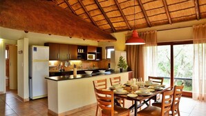 Una cocina con una isla central, sillas de madera y una mesa de comedor preparada para cuatro comensales.