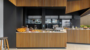 A modern breakfast bar with a wooden slatted design, a coffee machine, and a variety of breakfast items. - Numa Berlin Drift (Berlin)