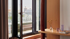 A modern room with a large window, a wooden desk, and a vase with decorative items. - Numa Berlin Drift (Berlin)