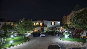 A residential building with a stone facade, a covered outdoor seating area, and a driveway with parked cars. - Da Milena (Orbetello)