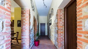A hallway with brick walls, a wooden door, and a potted plant. - Da Milena (Orbetello)