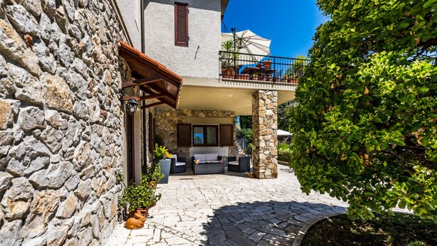 A stone building with a balcony, outdoor seating, and a stone pathway. - Da Milena (Orbetello)