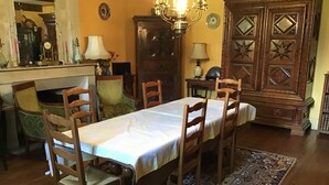 Un comedor con una larga mesa, sillas de madera, una araña y un tapete estampado.