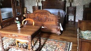 Un dormitorio tradicional con cama de madera, mesita de noche, cómoda y espejo.