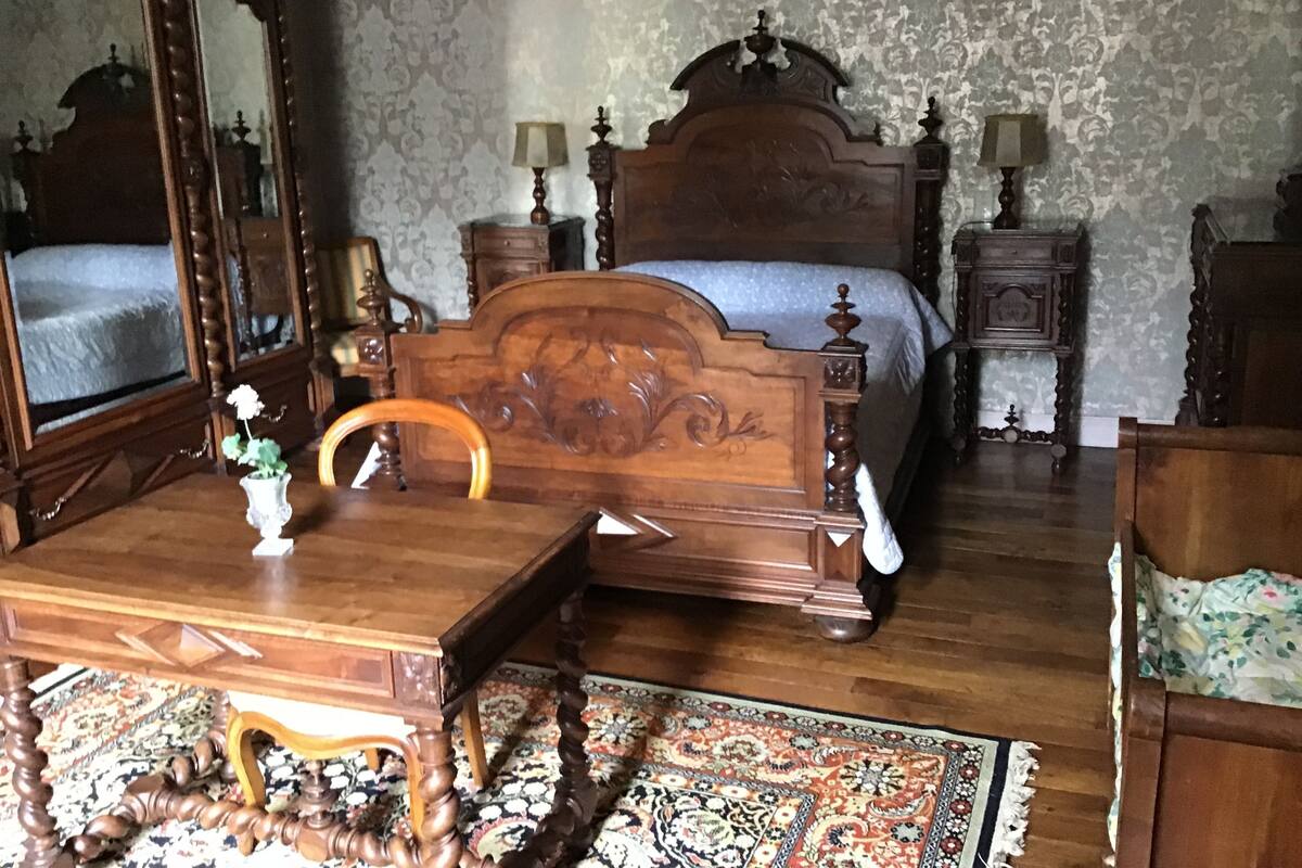A traditional bedroom with a wooden bed, a nightstand, a dresser, and a mirror.