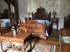 A traditional bedroom with a wooden bed, a nightstand, a dresser, and a mirror.