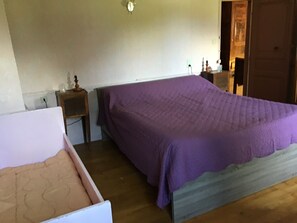 A room with a bed, a nightstand, and a wooden floor.