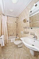 A bathroom with a bathtub, toilet, and sink. There is a shower curtain, a towel rack, and a mirror.