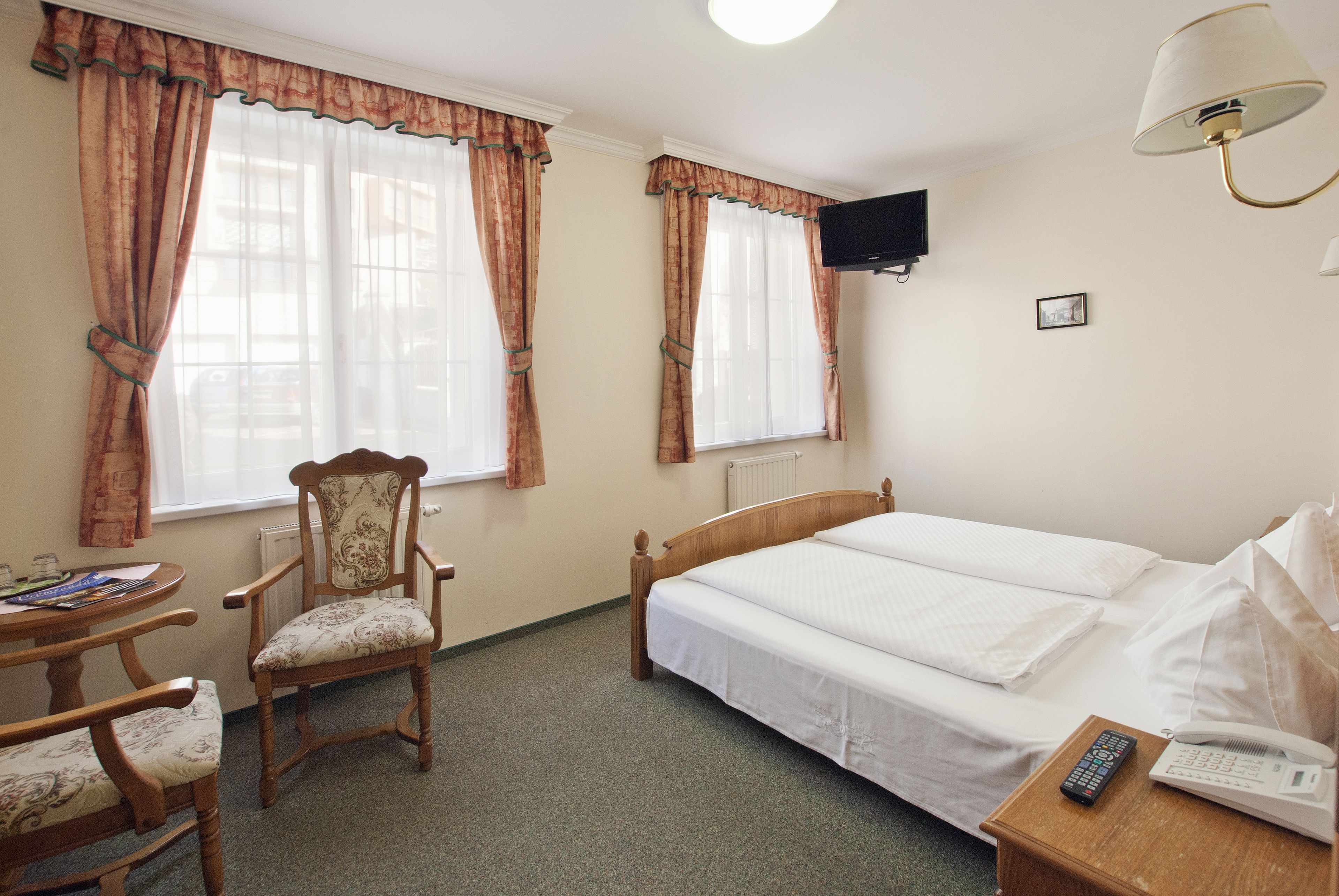Een hotelkamer met een bed, een stoel, een tafel, een televisie en een lamp.