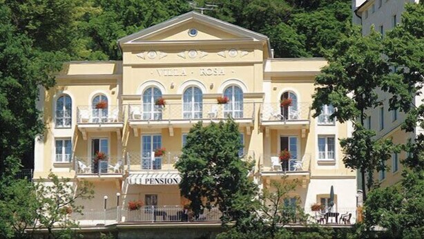 Un edificio con fachada clásica, varios balcones y un letrero que dice "Villa Rosa Pension".