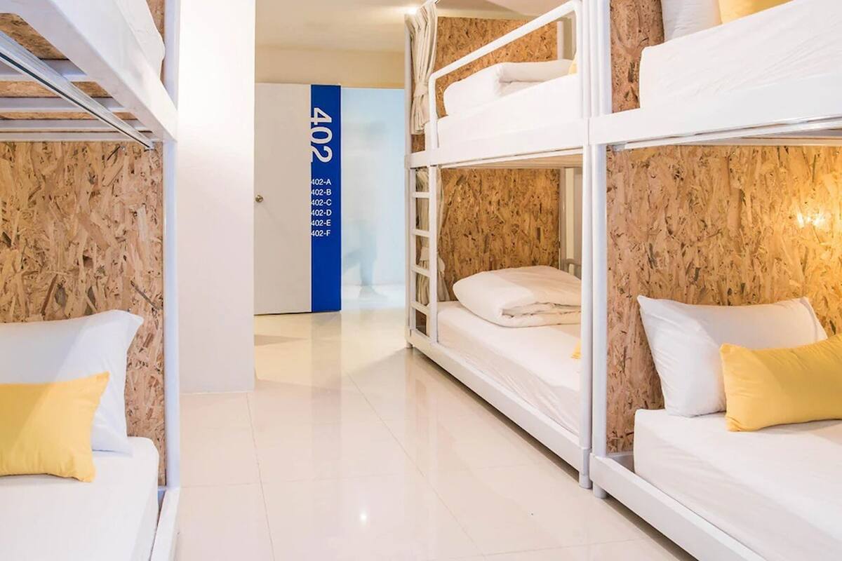 Ein Hotelzimmer mit Etagenbetten, einem weißen Sofa und einer blauen Wand mit Zimmernummern.