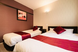 Ein Hotelzimmer mit zwei Betten, jeweils mit einer roten und weißen Bettdecke, einem Nachttisch und einem an der Wand hängenden Gemälde.
