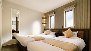 Habitación de hotel con dos camas, un espejo grande y dos ventanas con cortinas.