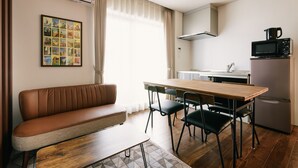 Una kitchenette moderna con microondas, refrigerador y una zona de comedor con mesa y sillas de madera.