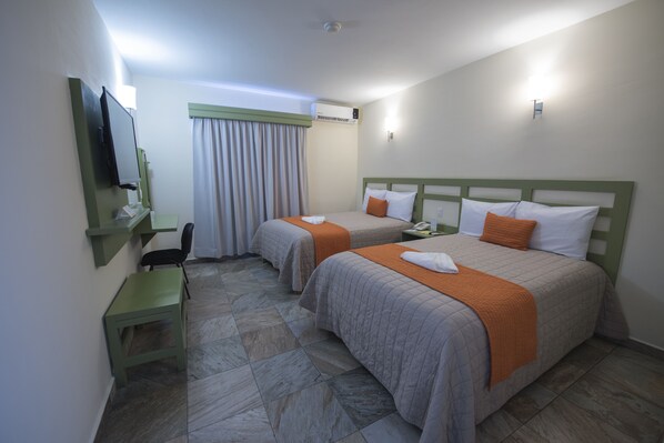 A hotel room with two beds, a desk, a chair, a TV, and a window with curtains.
