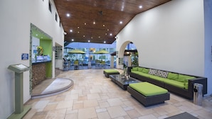 Un vestíbulo amplio con una mesa de recepción, zona de estar y sombrillas exteriores.