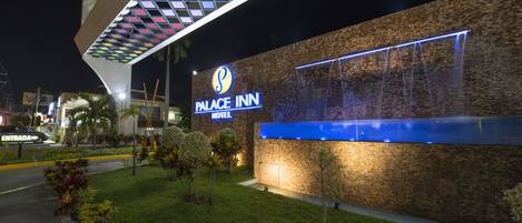 Een hotel genaamd "Palace Inn" met een modern architectuurontwerp, met een opvallende entree en verzorgde beplanting.
