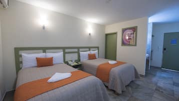 A hotel room with two beds, each with an orange blanket and white pillows, a green headboard, and a painting on the wall.